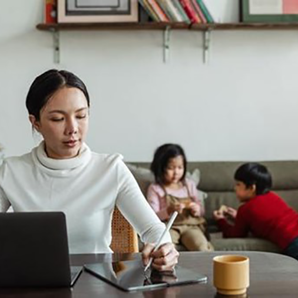 Image of a woman working with her children in the background